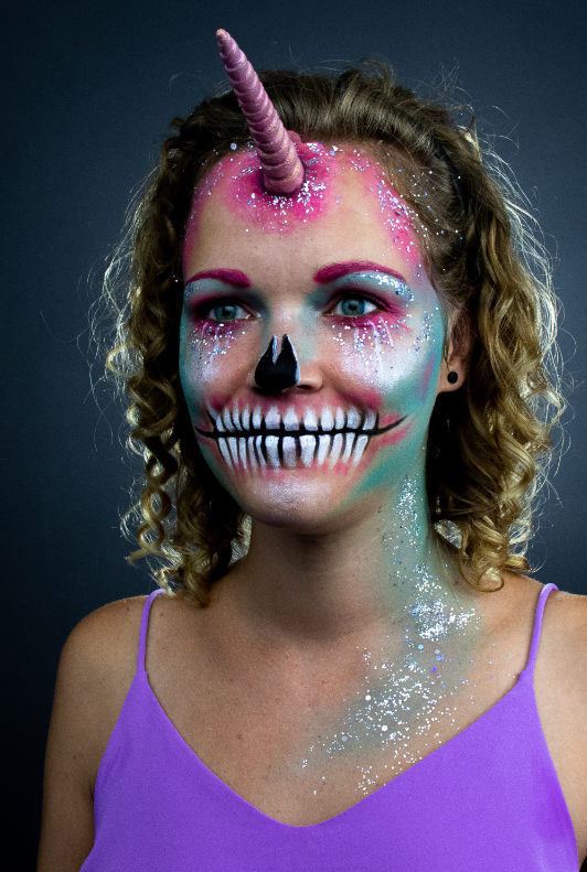 Vrouw met glitterende unicorn schmink voor Halloween